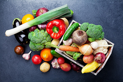 木箱与秋收蔬菜和根作物在黑色厨房桌子上俯视。