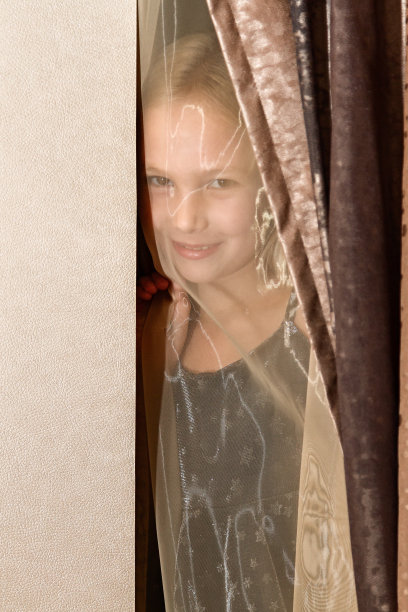 女孩躲在窗帘后面