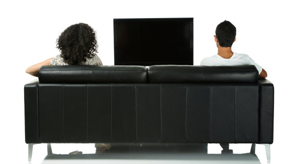 在客厅沙发上看电视的夫妇