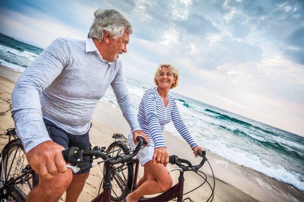 在海边骑自行车的一对老夫妇