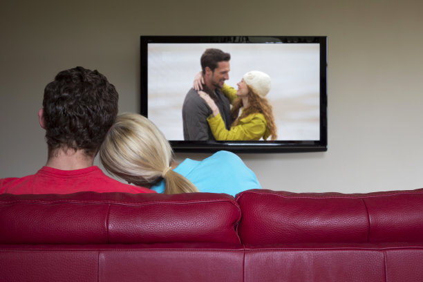 在客厅沙发上看电视的夫妇