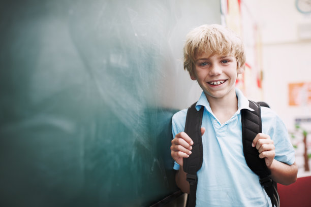 微笑的小学生站在黑板上