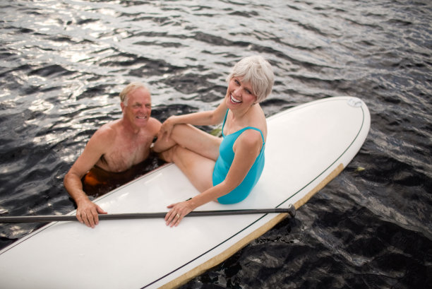拿着冲浪板的快乐老年妇女