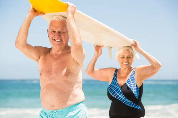 拿着冲浪板的快乐老年妇女