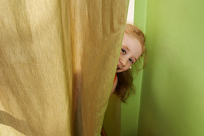 女孩躲在窗帘后面