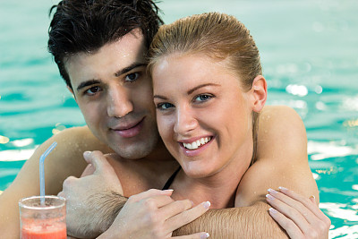 年轻夫妇在游泳池里拥抱