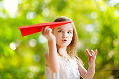 在公园里玩纸飞机的女孩
