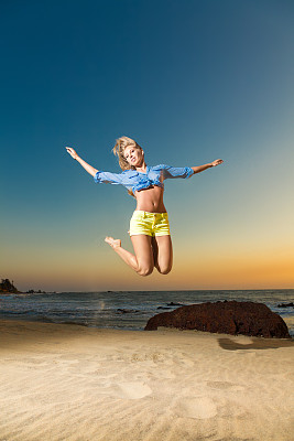 海滩上跳跃的金发美女