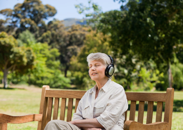 在长椅上听音乐的老年妇女