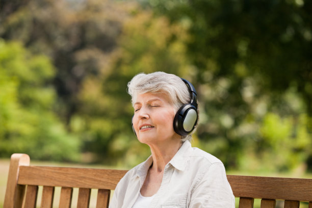 在长椅上听音乐的老年妇女