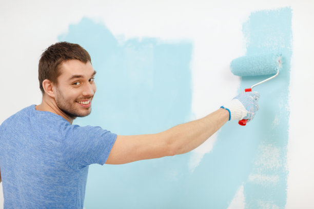 在墙壁上刷油漆的男人