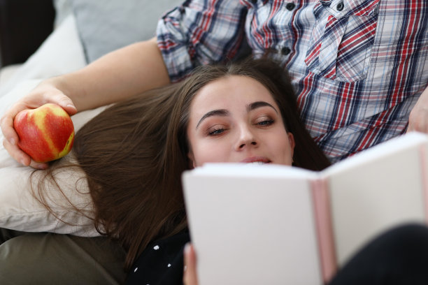 年轻女子躺在沙发上看书