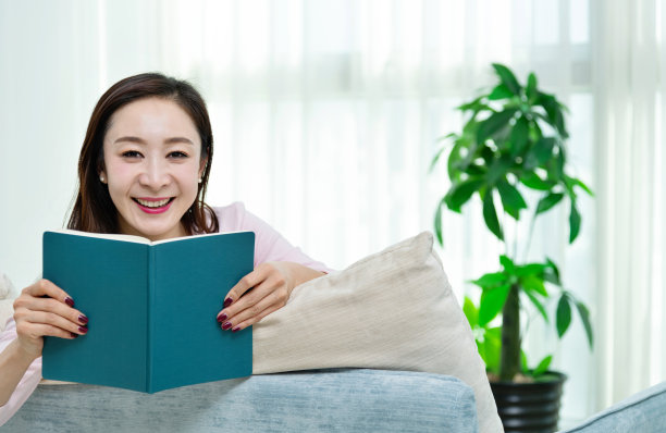 微笑的女人趴在沙发上看书