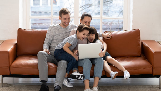 家人坐在沙发上使用笔记本电脑