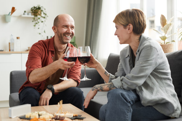 沙发上干杯喝红葡萄酒的夫妇