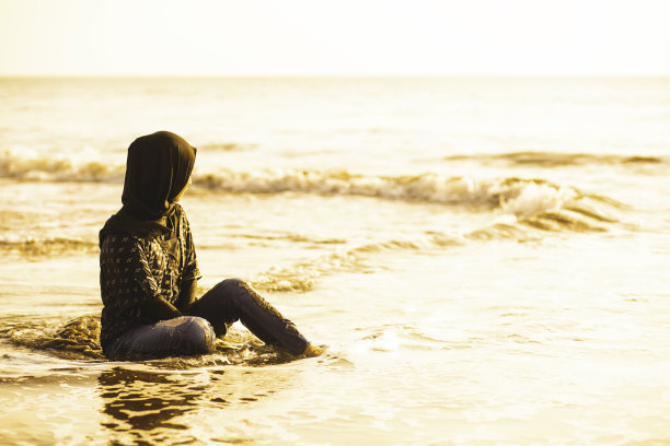 孤独的亚洲人在夏天独自坐在沙滩上看海。