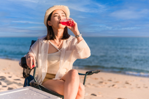 坐在海边拿着鸡尾酒的女人