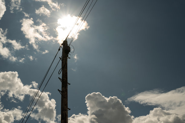 蓝天白云背景前的供电输电塔