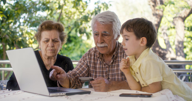 孙子和奶奶在家里用笔记本电脑