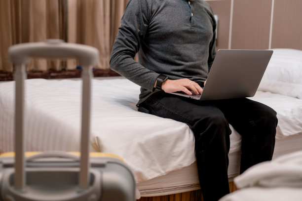 微笑的男子坐在床上用笔记本电脑