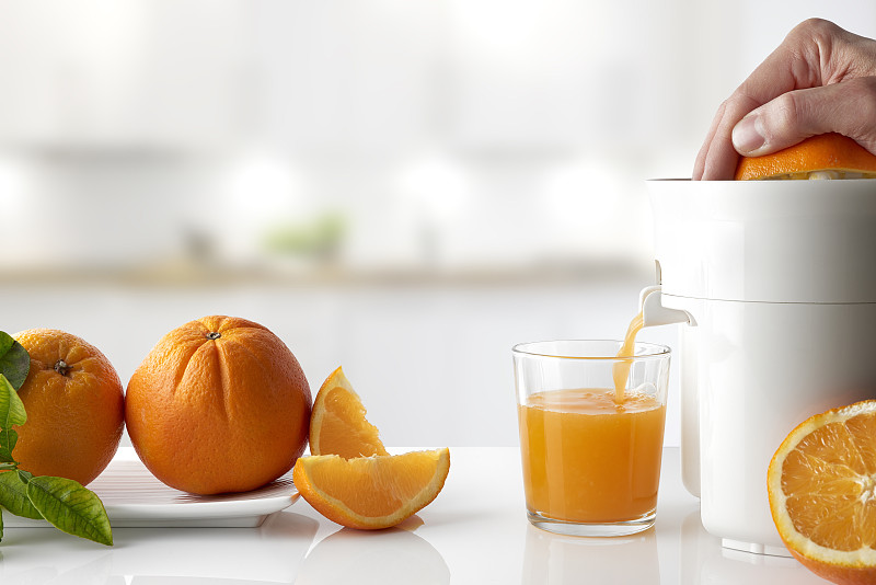 水平画幅,橙子,手,平衡折角灯,餐桌,榨汁机,电动榨汁机,正面视角,玻璃,果汁