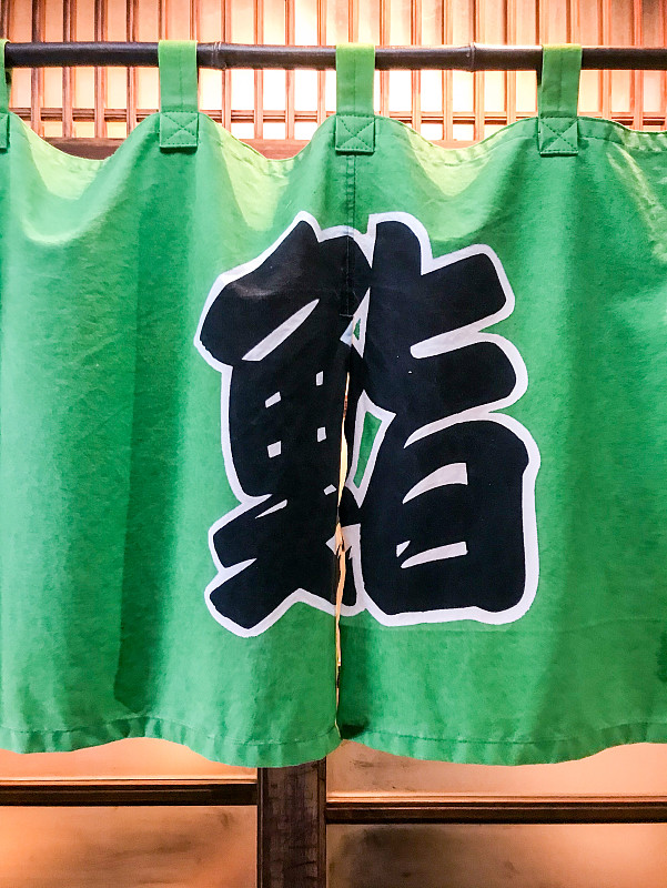 Kanji,“sushi”,on,green,noren,curtain,hanging,at,front,door